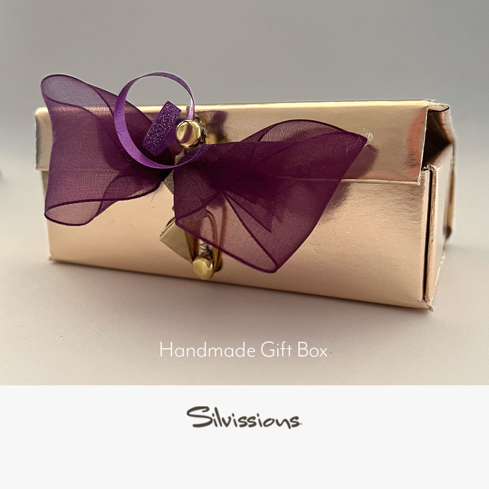 Gold gift box with a purple bow on a beige background, featuring the brand 'Silvissions'.