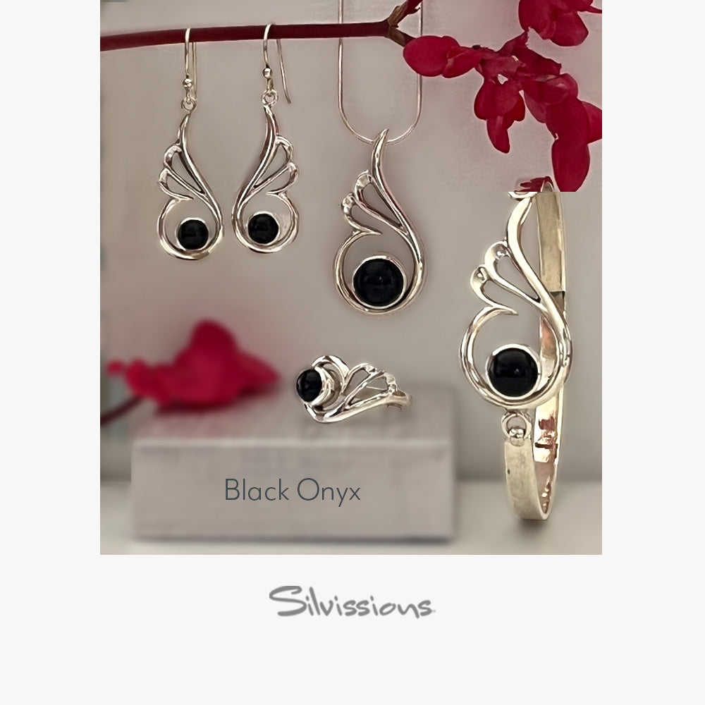 Silver jewelry set with black onyx gemsstones including earrings, a ring, and a bracelet, displayed against a neutral background.
