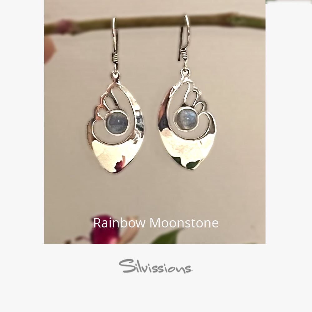 Silver earrings with rainbow moonstone stones on a beige background, branded 'Silvissions'.