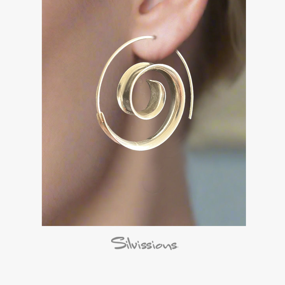 Silver spiral earring worn on an ear with a blurred background