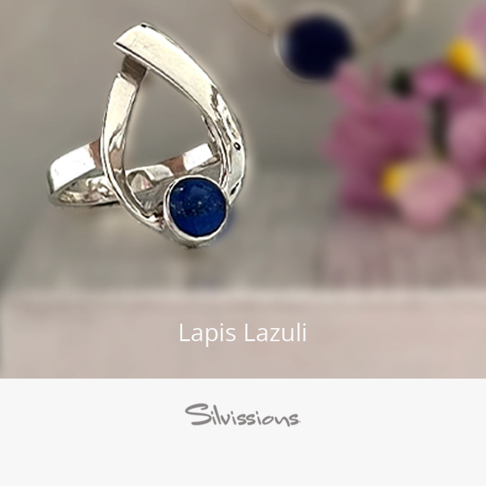 Silver ring with a blue stone on a beige background, branded 'Silvissions'.
