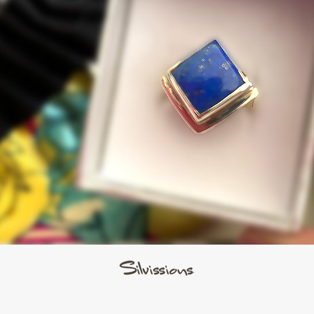 Lapis Lazuli ring with silver band in a white box, blurred background with colourful flowers.