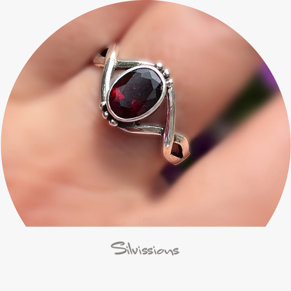 Silver ring with a red gemstone worn on a finger, branded 'Silvissions'.
