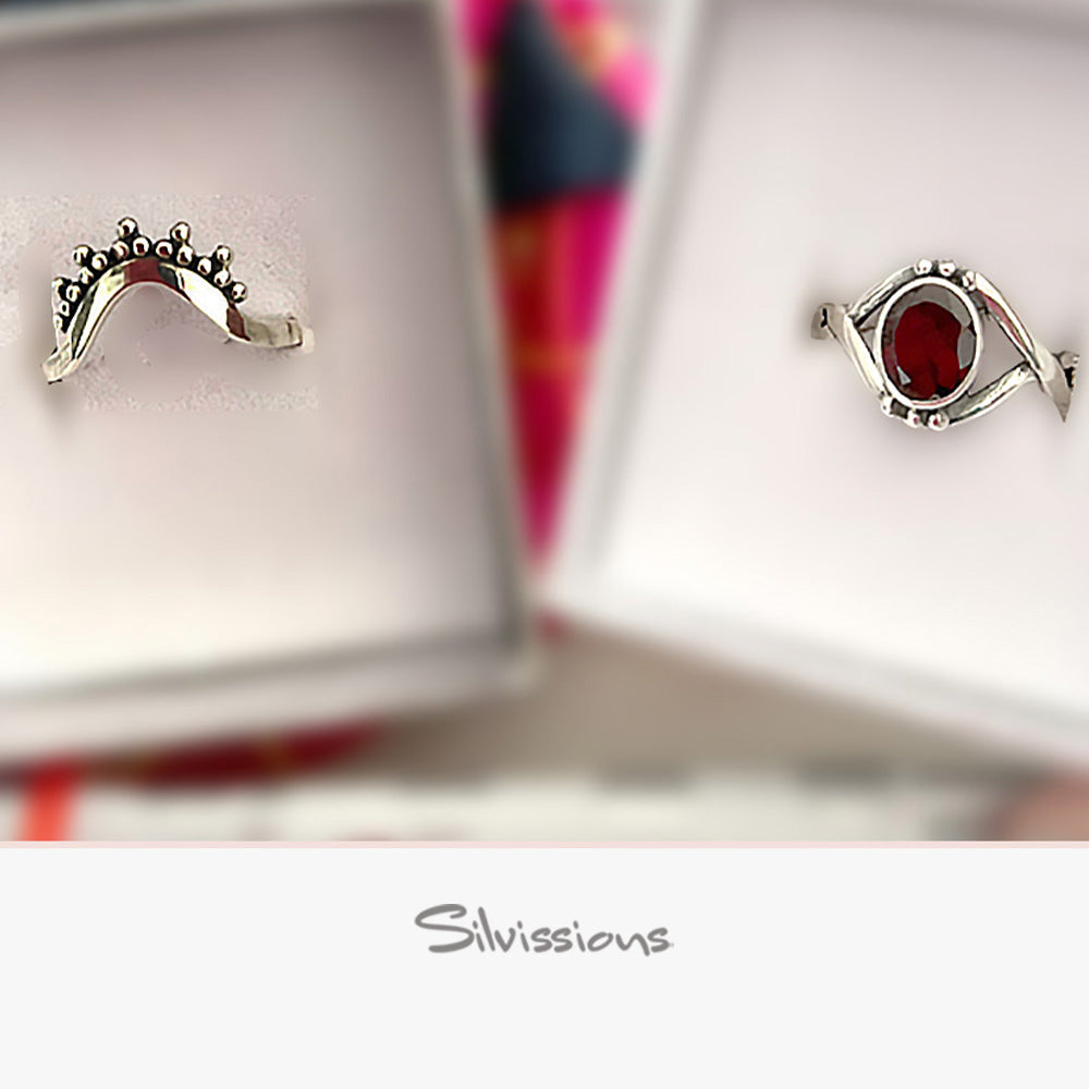 Two silver rings with gemstones on a blurred background, featuring the brand 'Silvissions'.