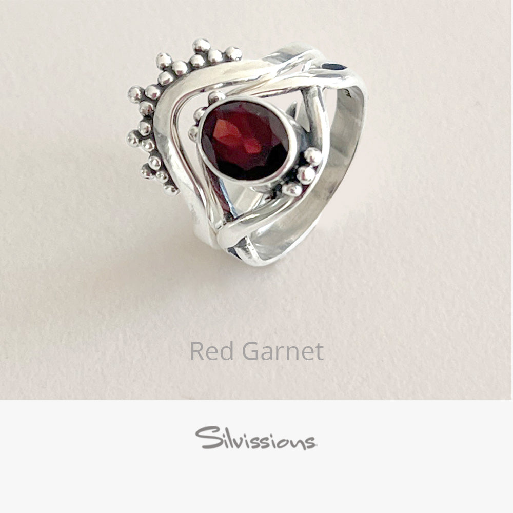 Silver ring with a red gemstone on a light gray background, branded 'Silvissions'.