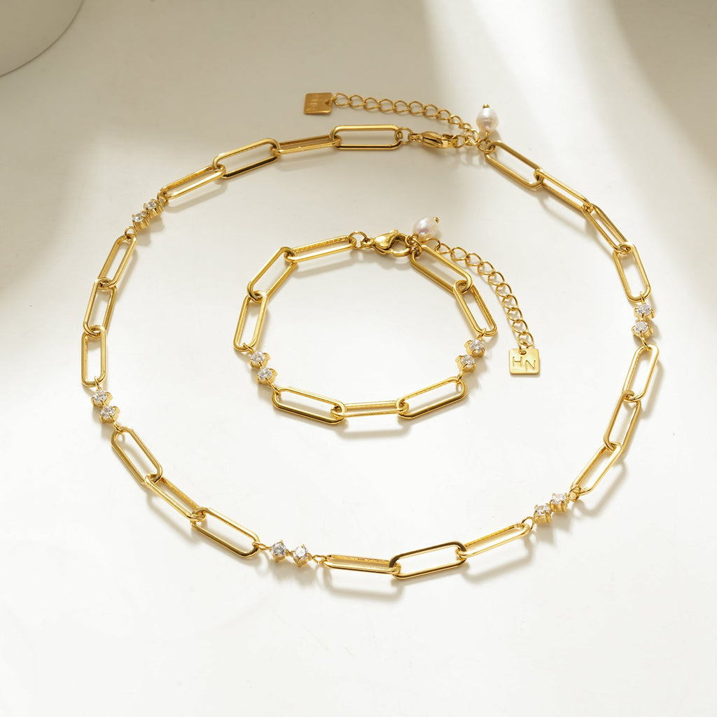 Gold chain necklace and bracelet set on a light background