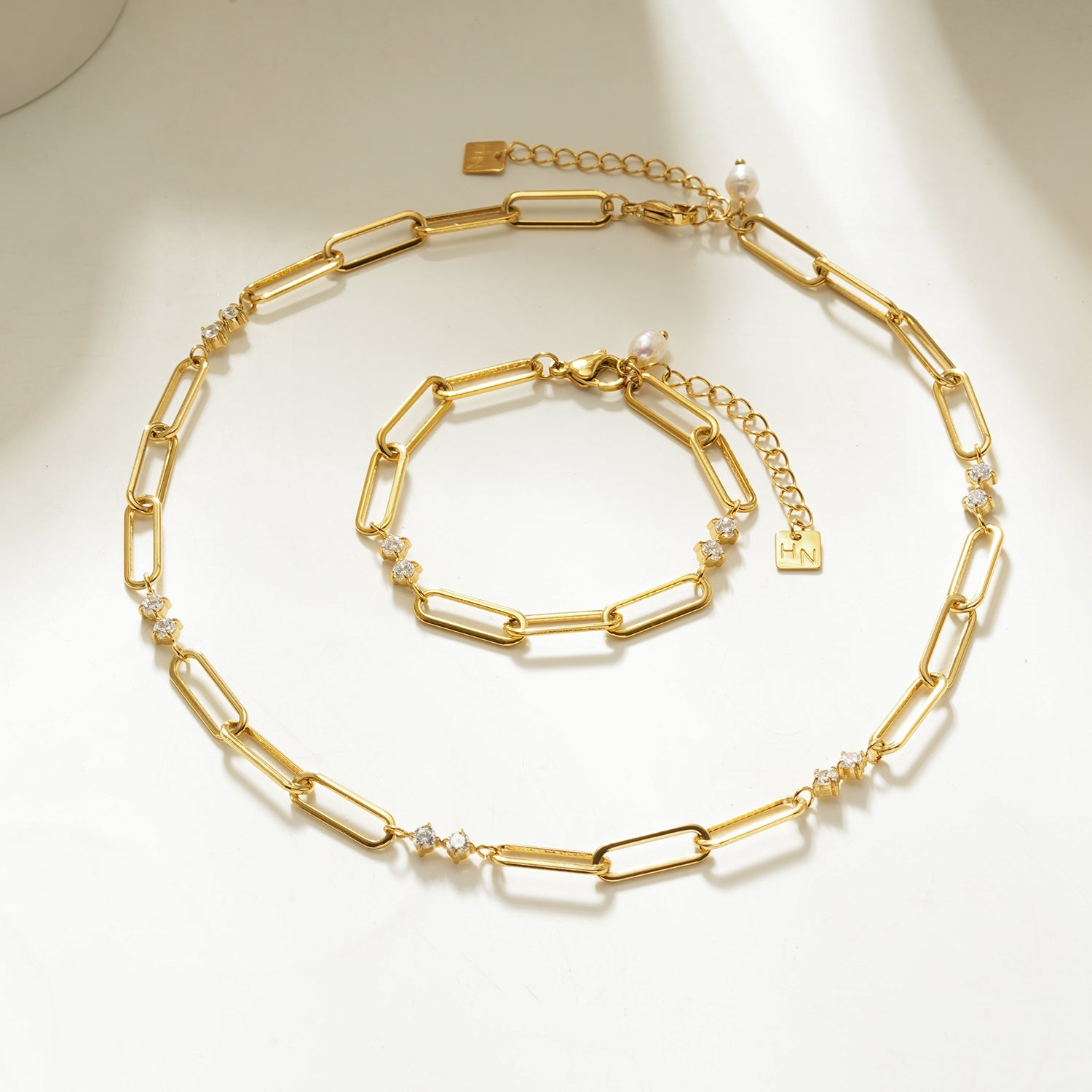 Gold chain necklace and bracelet set on a light background