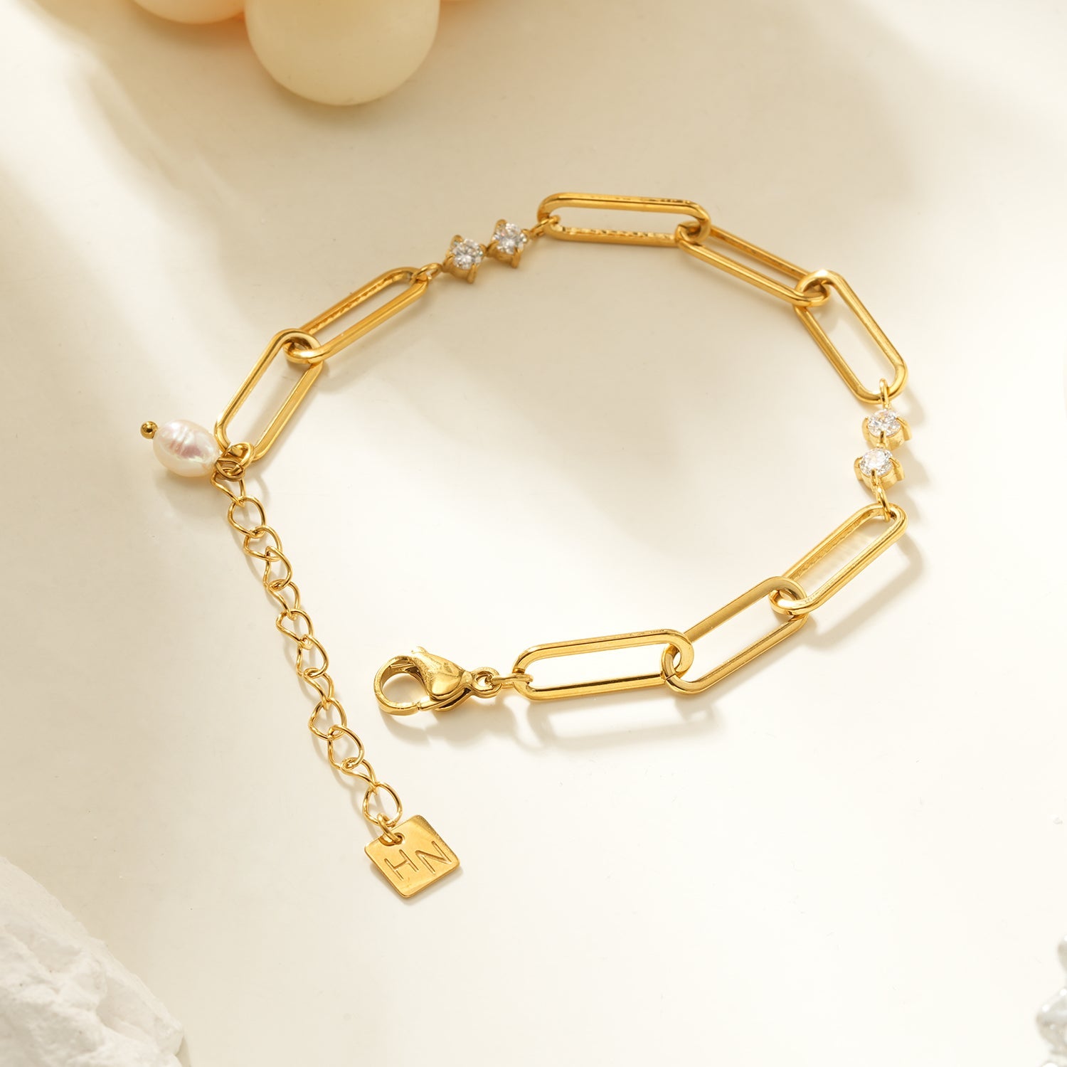 Gold bracelet with a clasp and charm on a light background