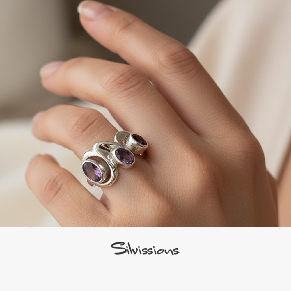 Hand wearing a silver ring with purple gemstones, branded 'Silvissions'.