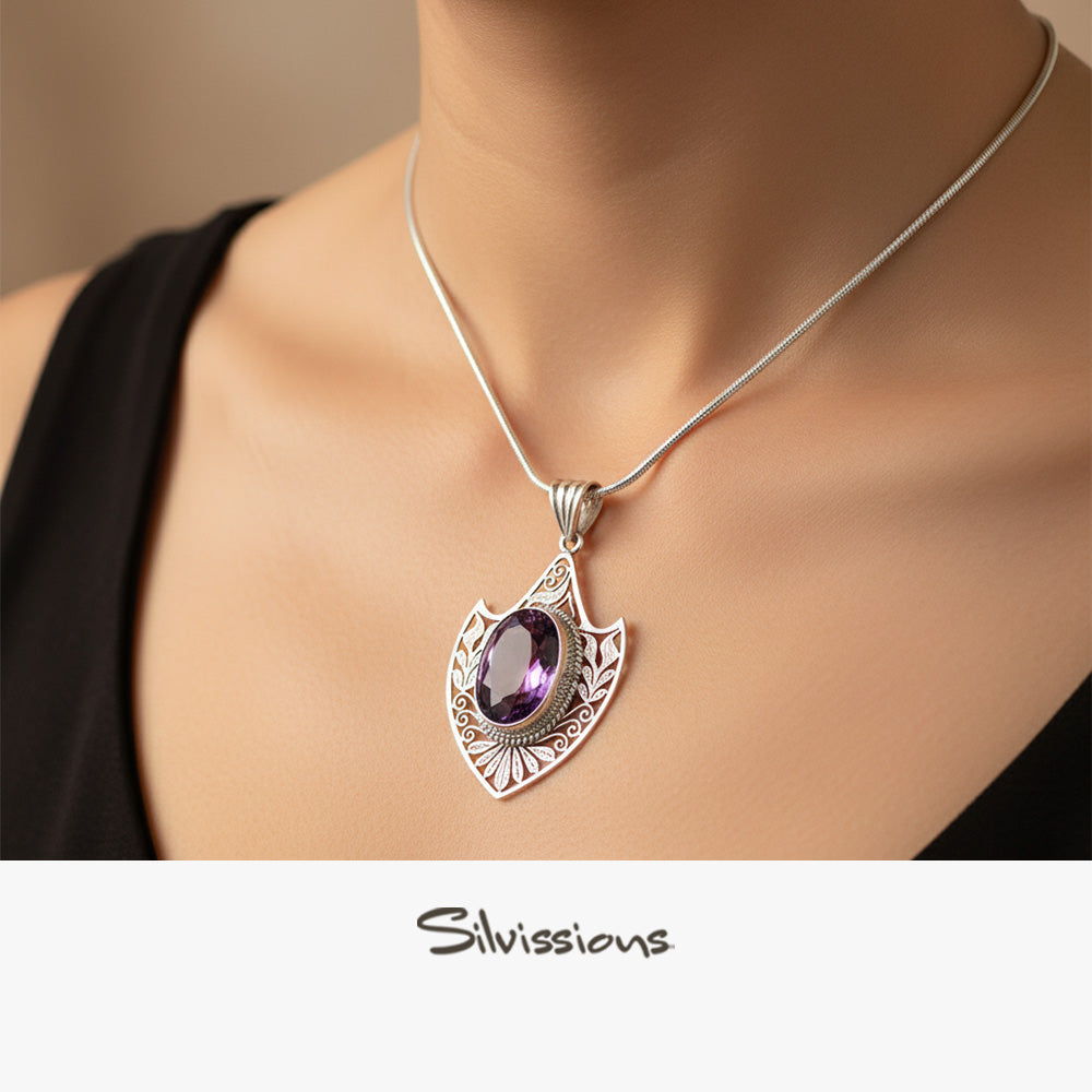 A sterling silver amethyst pendant necklace with a rope chain, displayed on a woman's neck.