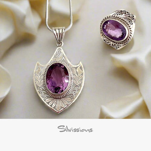 Silver pendant with purple gemstone on a white fabric background, featuring the brand 'Silvissions'.