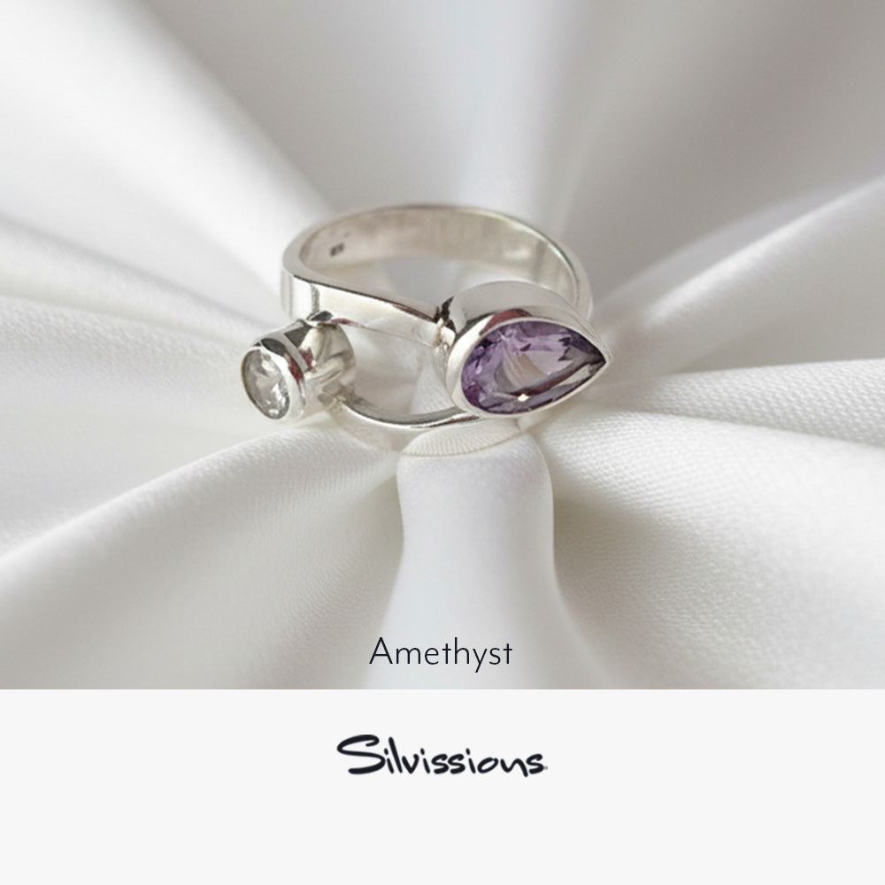 Silver ring with amethyst stone on white fabric, featuring the brand 'Silvissions'.
