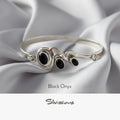 Silver bracelet with black onyx stones on a white fabric background, featuring the brand 'Silvissions'.