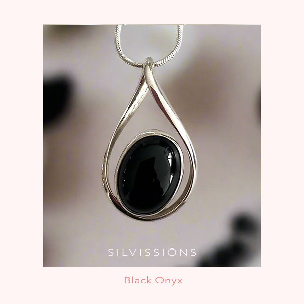 Silver pendant with black onyx stone on a blurred background, featuring the brand 'Silvissions'.