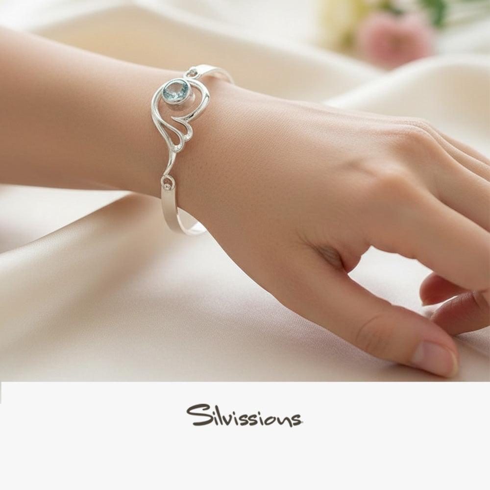Silver bracelet with a blue topaz gemstone on a person's wrist, brand 'Silvissions' visible