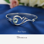 Silver bracelet with blue topaz gemstone on a blue fabric background, featuring the brand 'Silvissions'.