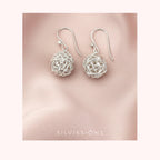 Silver bridal earrings on a pink fabric background with 'Silvissions' branding.