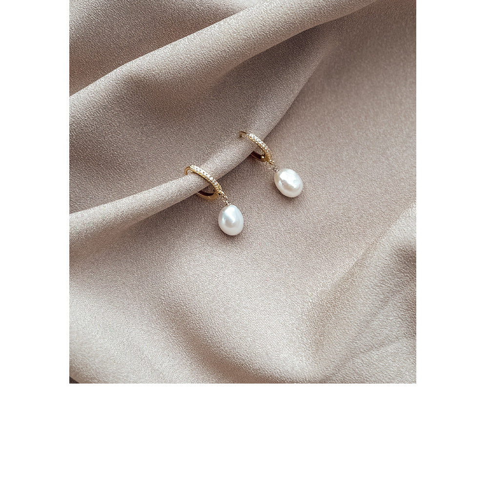 Pair of pearl earrings on a beige fabric background