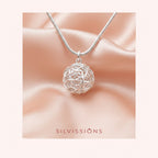 Silver necklace with a intricate pendant on a soft pink background, featuring the brand 'Silvissions'.