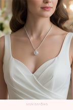 Woman wearing a silver necklace with a pendant, branded 'Silvassions', against a blurred background.