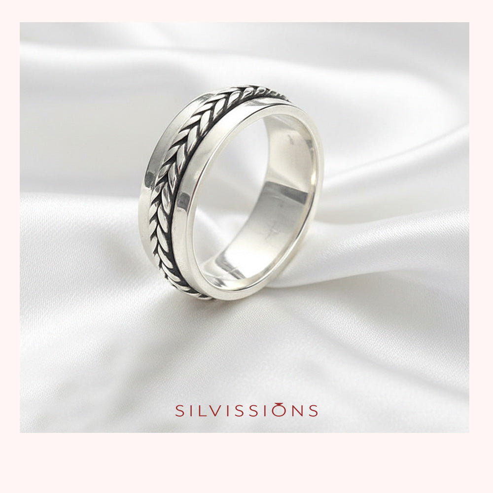 Silver ring with intricate design on a white satin background, featuring the brand 'Silvissions'.