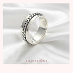 Silver ring with intricate design on a white satin background, featuring the brand 'Silvissions'.