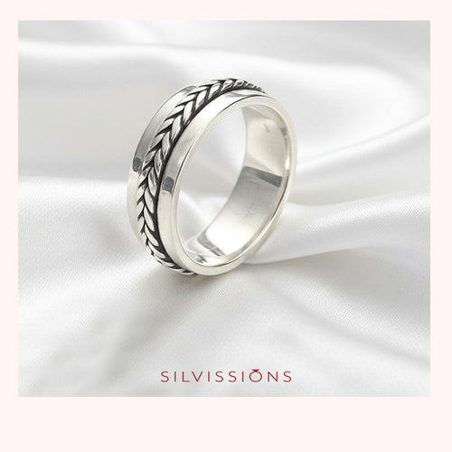 Silver ring with intricate design on a white satin background, featuring the brand 'Silvissions'.