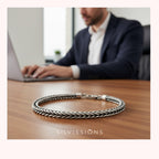 Silver bracelet on a desk with a blurred person using a laptop in the background, featuring the Silvissions brand.