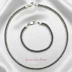 Silver necklace and bracelet set on a satin surface with 'Silvissions' branding.