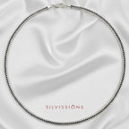 Silver necklace on a satin background with 'Silvissions' branding.