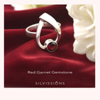 Silver ring with red garnet gemstone on red fabric with white flowers