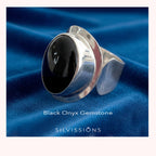 Silver ring with black onyx gemstone on a blue fabric background, featuring the Silvissions brand. 