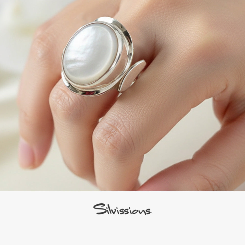 Silver ring with a large mother of pearl gemstone on a hand, branded 'Silvissions'.