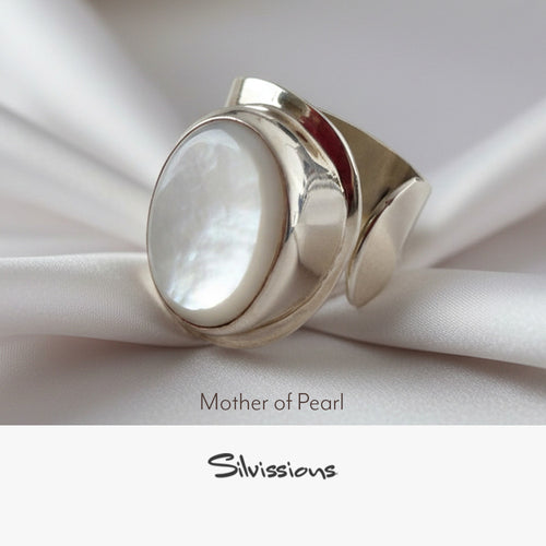 Silver ring with mother of pearl stone on white fabric, featuring Silvissions brand.