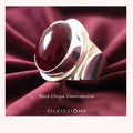 Silver ring with a red onyx gemstone on a burgundy fabric background, featuring the brand 'Silvissions'.