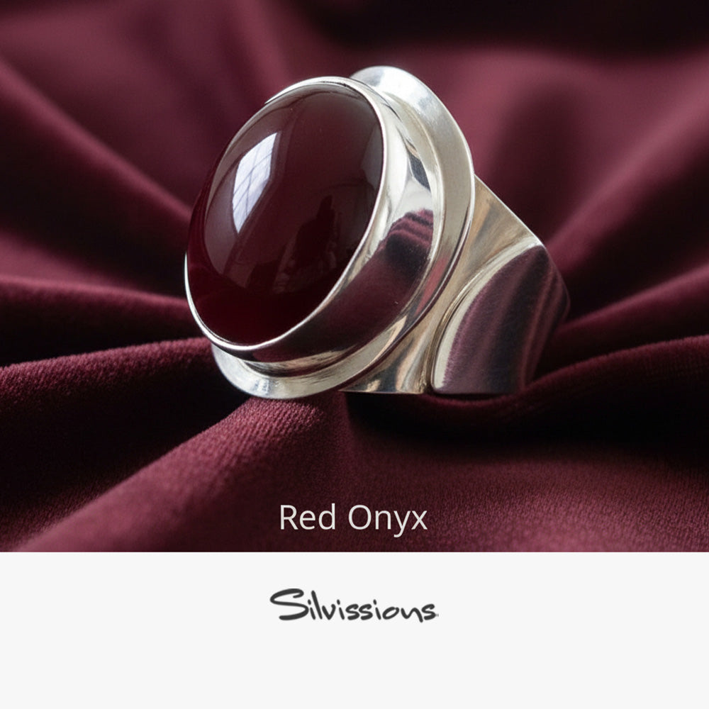 Silver ring with red onyx stone on burgundy fabric, branded 'Silvissions'.