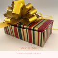 A rectangular gift box wrapped in red, green, and gold vertical striped paper, topped with a large shiny gold bow. The words 'SILVISSIONS' and 'Striped Gift Box' appear below the product on a white background.