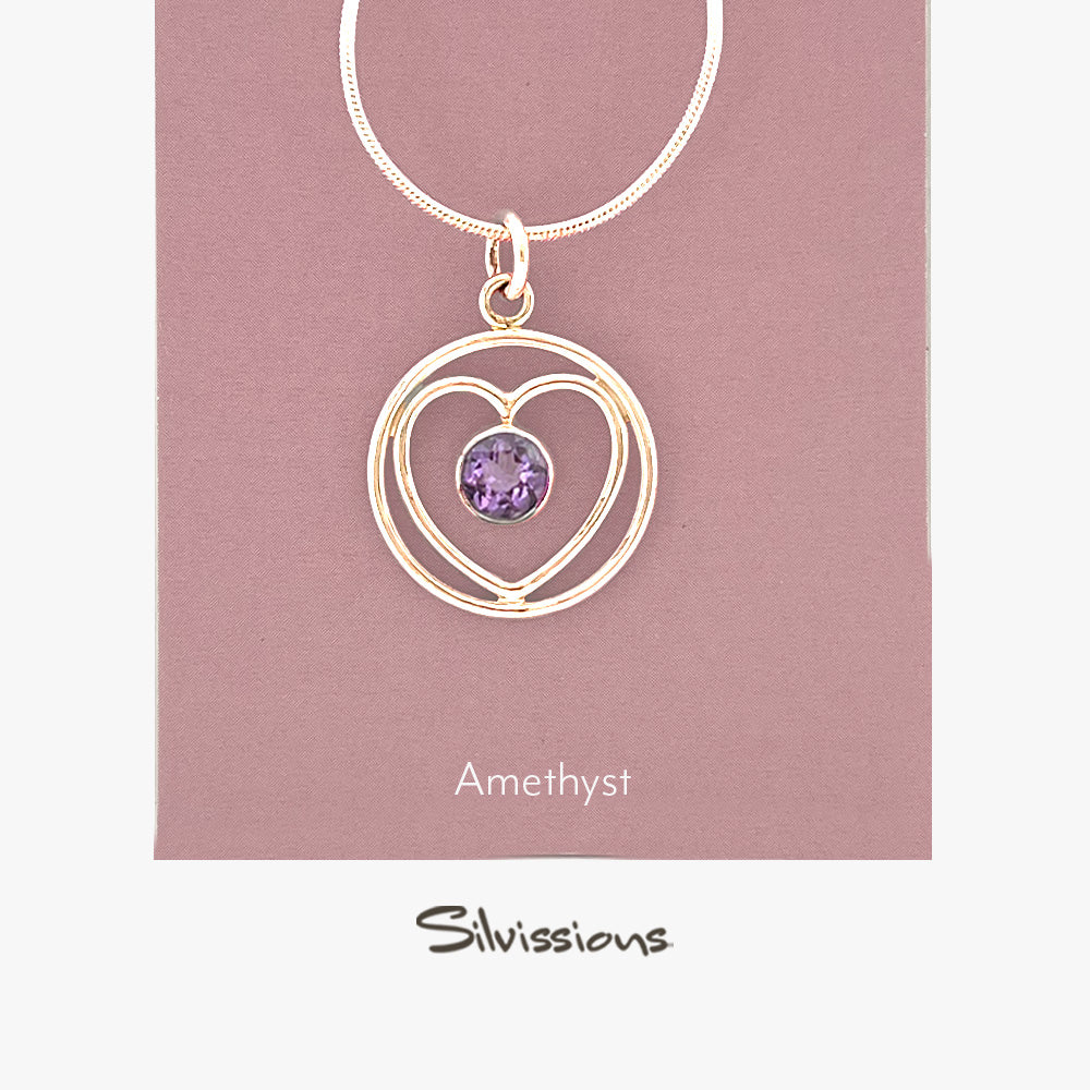 A sterling silver heart-shaped pendant necklace with an amethyst gemstone in the center, displayed against a purple background with the brand name 'Silvissions' mentioned at the bottom.
