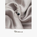Silver necklace with heart-shaped pendant featuring a black gemstone on a satin background, branded 'Silvissions'.