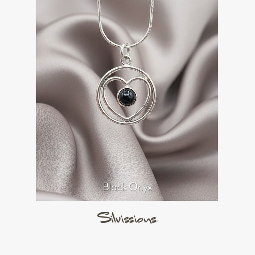 Silver necklace with heart-shaped pendant featuring a black gemstone on a satin background, branded 'Silvissions'.