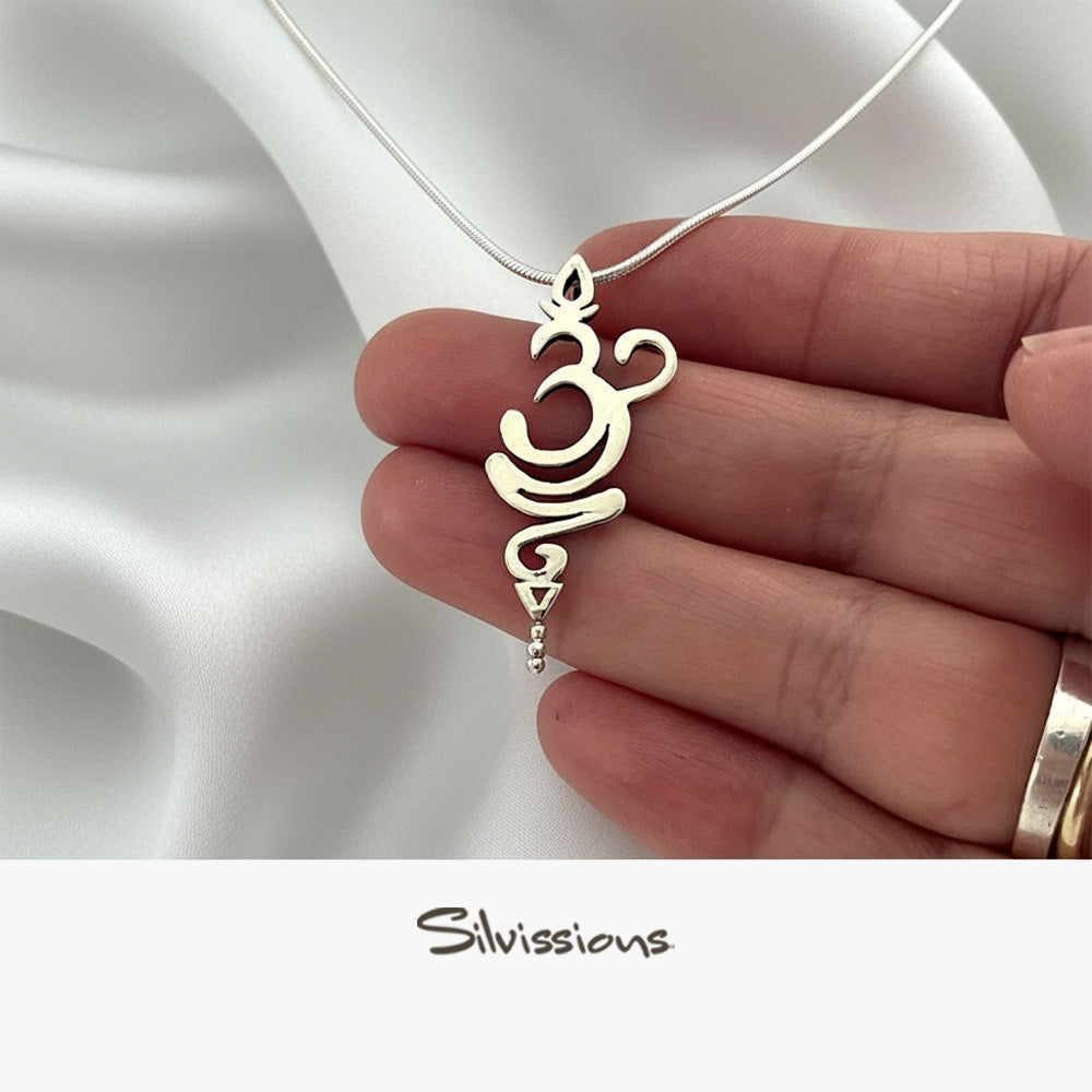 Silver Om symbol necklace held by a hand on a white fabric background, with 'Silvissions' branding.