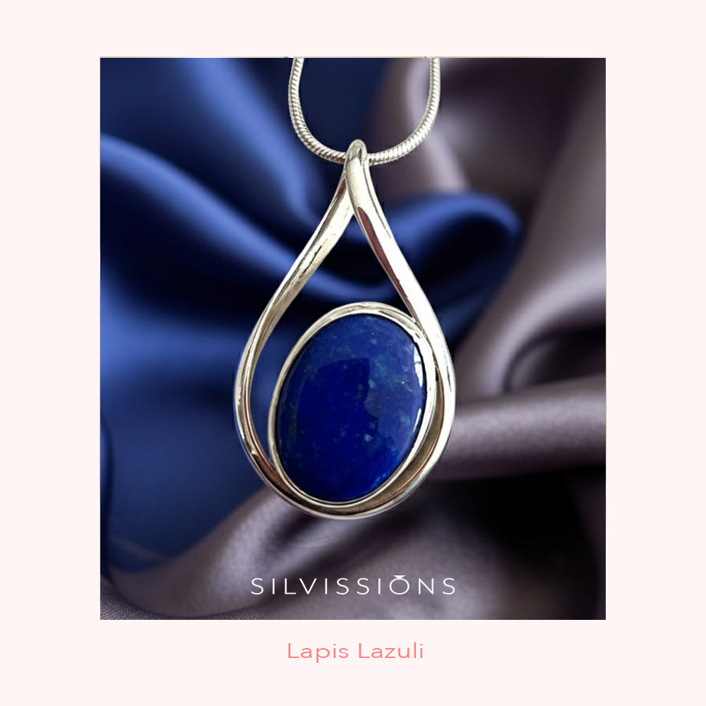 Silver pendant with blue stone necklace on a dark fabric background, featuring the brand 'Silviissions'.