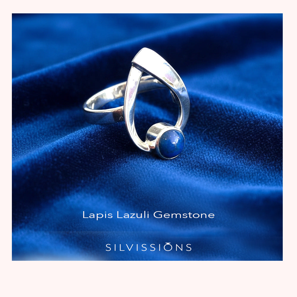 Silver ring with lapis lazuli stone on blue fabric, featuring 'Silvissions' brand.