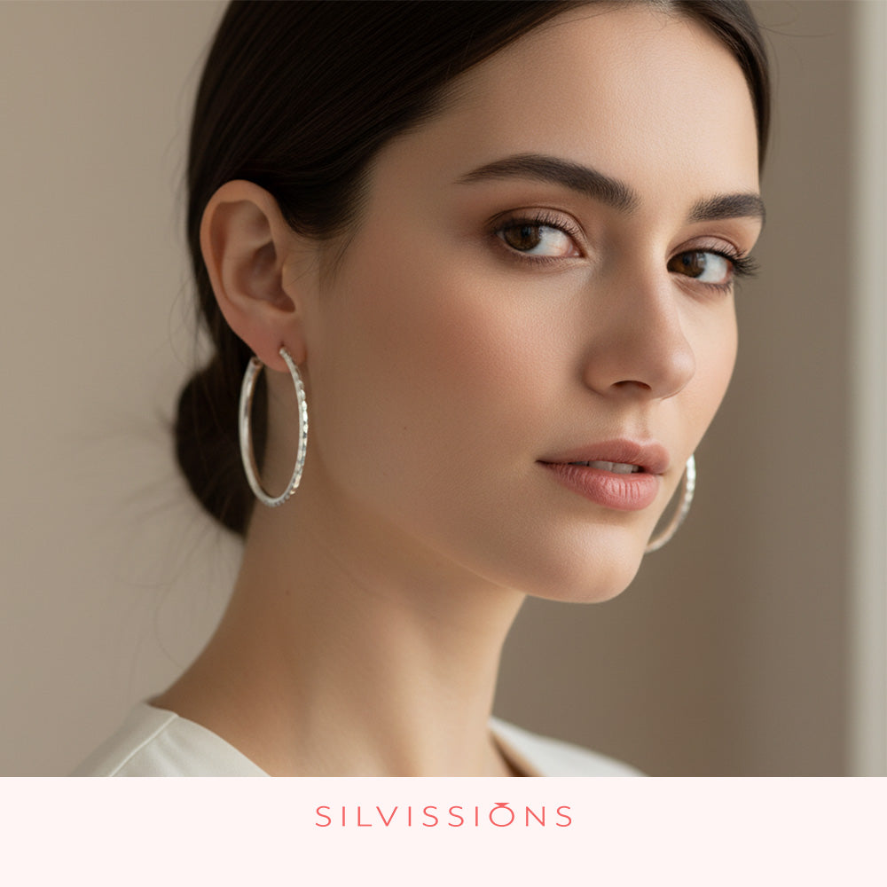 Woman wearing hoop earrings with a neutral background, featuring the brand 'Silvissions'.
