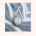 Silver pendant with rainbow moonstone on a white satin background, featuring the brand 'Silvissions'.