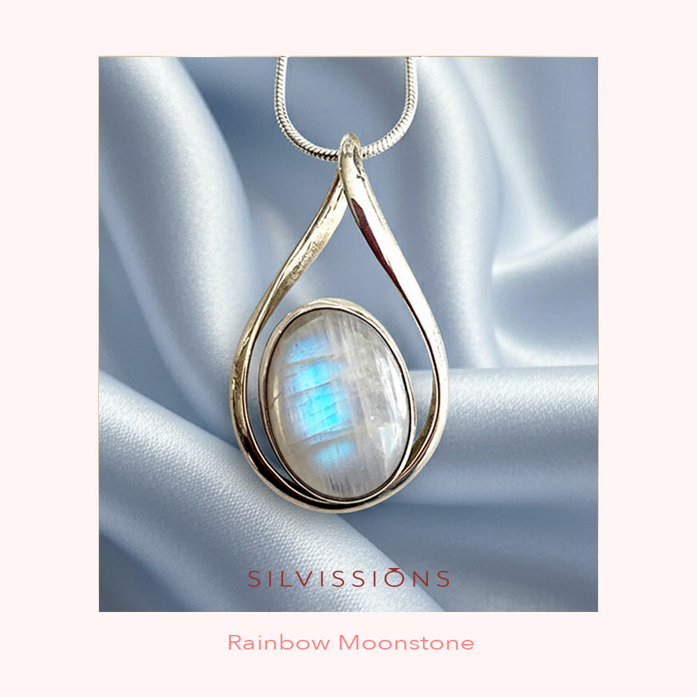 Silver pendant with rainbow moonstone on a white satin background, featuring the brand 'Silvissions'.