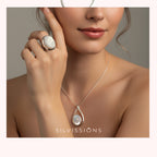 Woman wearing a silver ring and necklace with a visible brand logo on a neutral background