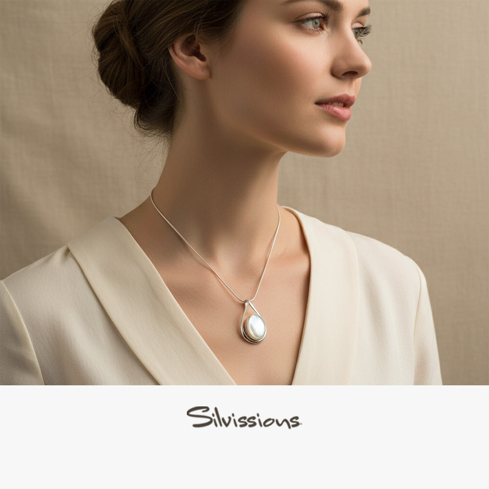 Woman wearing a necklace with a teardrop pendant, branded 'Silvassions', against a neutral background.