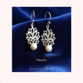 Silver lotus flower earrings with pearls on a blue satin background, branded 'Silvissions'.