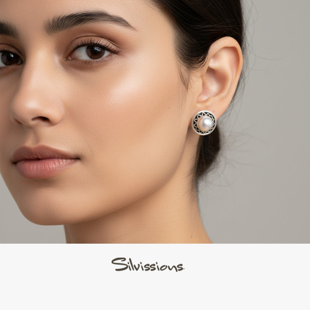 Close-up of an ear wearing a sterling silver earring with a pearl centre, branded 'Silvissions'.